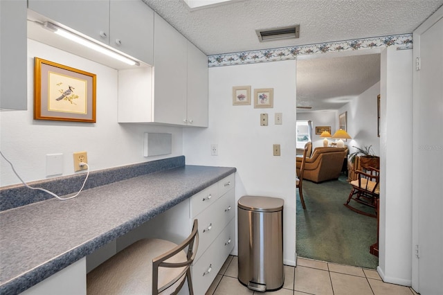 8 Glencoe Pl Unit 305, Dunedin, FL 34698 - kitchen featuring a textured ceiling, light tile patterned floors, dark countertops, and white cabinetry