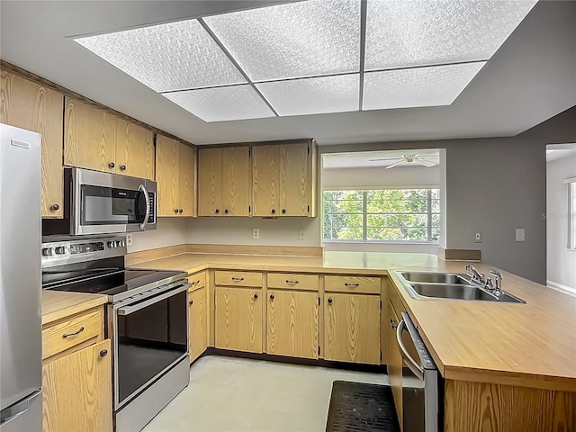 kitchen featuring appliances with stainless steel finishes, a sink, a ceiling fan, and a peninsula