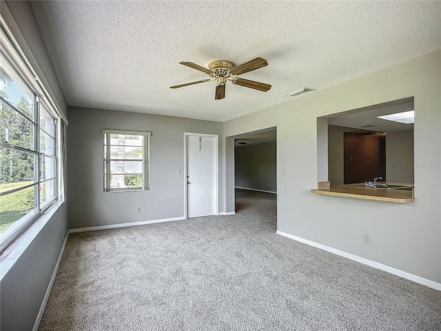unfurnished room with a textured ceiling, baseboards, carpet floors, and a ceiling fan