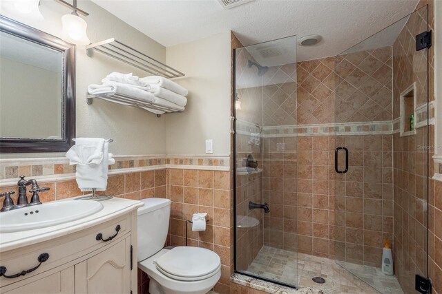 8240 144th Ln, Seminole, FL 33776 - bathroom featuring toilet, vanity, a stall shower, wainscoting, and tile walls