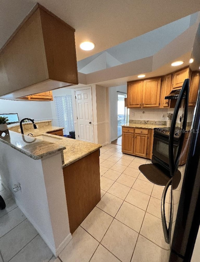 2528 Deerbrook Dr, Lakeland, FL 33811 - kitchen featuring light tile patterned flooring, light stone countertops, a sink, brown cabinets, and a peninsula