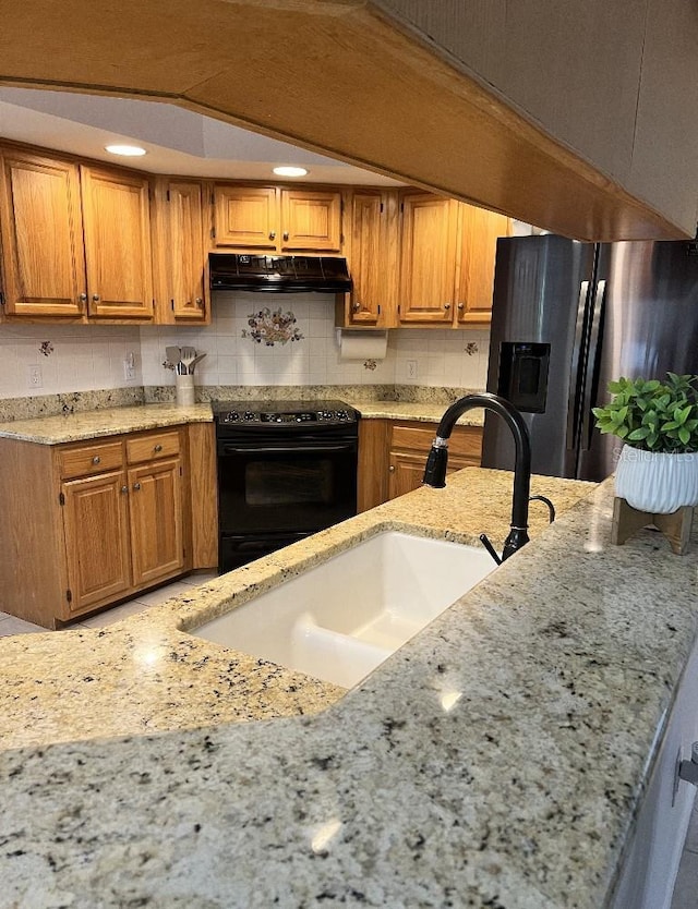 2528 Deerbrook Dr, Lakeland, FL 33811 - kitchen featuring black range with electric stovetop, under cabinet range hood, stainless steel fridge, a sink, and light stone countertops