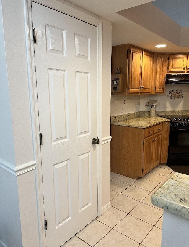 2528 Deerbrook Dr, Lakeland, FL 33811 - kitchen featuring black range with electric stovetop, under cabinet range hood, brown cabinets, and light tile patterned floors
