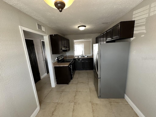 2557 Cedar Cypress Ct, Tampa, FL 33618 - kitchen featuring stainless steel appliances, a textured ceiling, light tile patterned floors, light countertops, and dark cabinets