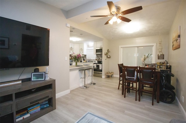 living area featuring ceiling fan, light wood-style floors, and baseboards