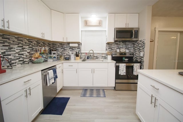 kitchen featuring appliances with stainless steel finishes, a sink, white cabinets, and backsplash