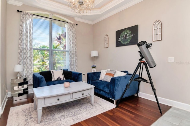 living room with crown molding, dark wood-style flooring, a chandelier, baseboards, and a tray ceiling