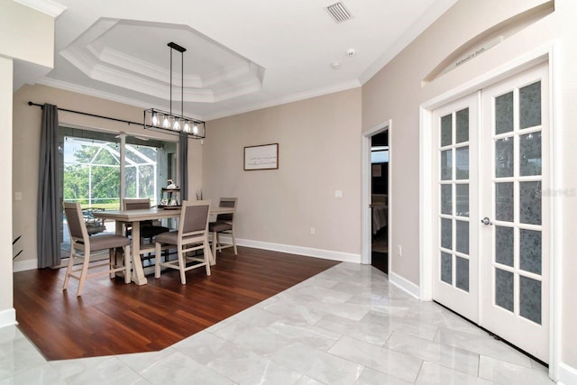 dining space featuring french doors, ornamental molding, a raised ceiling, baseboards, and wood finished floors