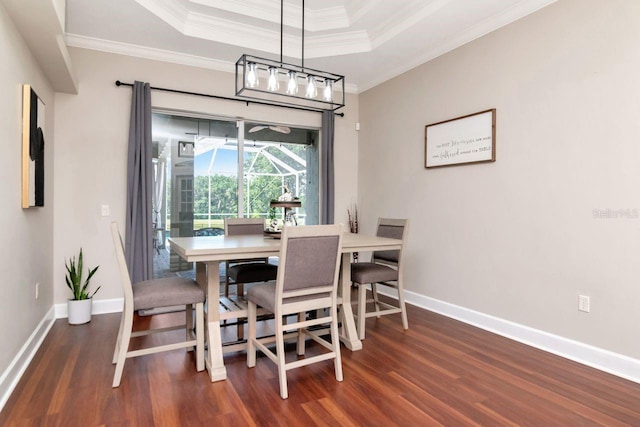 dining space with wood finished floors, baseboards, a raised ceiling, and ornamental molding
