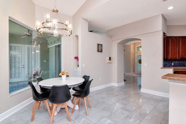 dining area with arched walkways, a chandelier, baseboards, and lofted ceiling