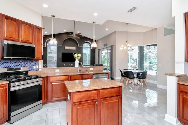 kitchen with appliances with stainless steel finishes, a sink, light marble finish flooring, open floor plan, and a peninsula