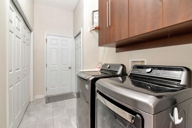 clothes washing area featuring cabinet space, separate washer and dryer, light marble finish floors, and baseboards
