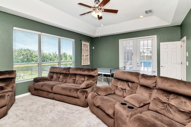 carpeted living room featuring ceiling fan, french doors, a tray ceiling, baseboards, and healthy amount of natural light