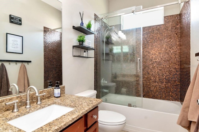 bathroom featuring toilet, vanity, and shower / bath combination with glass door