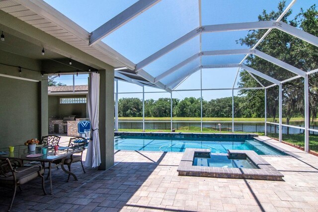 view of pool with a patio area, a lanai, view of wooded area, and a pool with connected hot tub