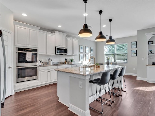 kitchen with stainless steel appliances, a sink, dark wood-type flooring, white cabinets, and recessed lighting