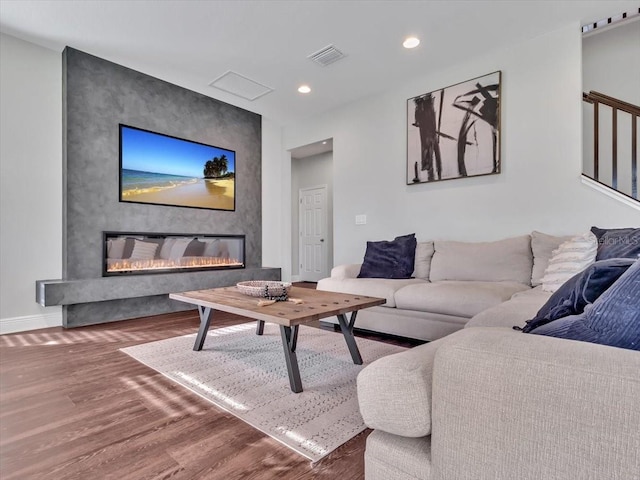 living area with a fireplace, wood finished floors, baseboards, and recessed lighting