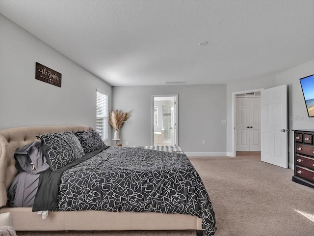 carpeted bedroom featuring connected bathroom and baseboards