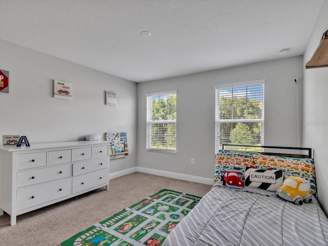 bedroom with light colored carpet and baseboards