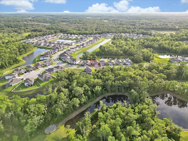 view of property location featuring nearby suburban area, a nearby body of water, and a forest