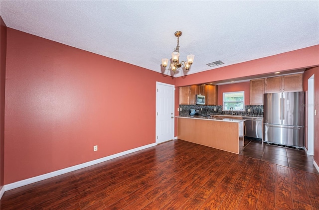 10051 82nd Ln, Seminole, FL 33777 - kitchen featuring stainless steel appliances, a chandelier, a peninsula, dark wood-style flooring, and backsplash