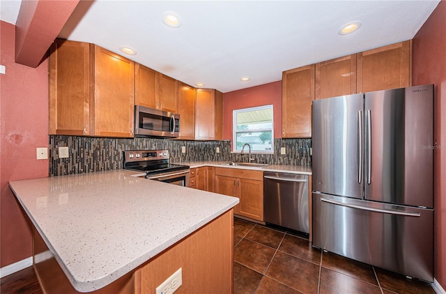 10051 82nd Ln, Seminole, FL 33777 - kitchen with stainless steel appliances, a sink, a peninsula, brown cabinets, and decorative backsplash