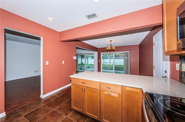 10051 82nd Ln, Seminole, FL 33777 - kitchen with a peninsula, a chandelier, stainless steel electric range, brown cabinetry, and decorative light fixtures