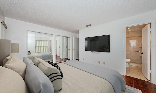 10051 82nd Ln, Seminole, FL 33777 - bedroom with multiple closets, wood finished floors, a textured ceiling, and ensuite bath