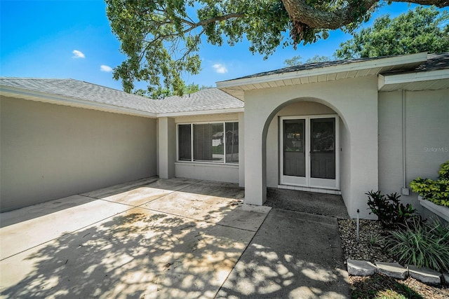 3305 Blythe Ave, Spring Hill, FL 34609 - doorway to property featuring stucco siding, a patio area, and a shingled roof