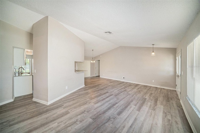3305 Blythe Ave, Spring Hill, FL 34609 - unfurnished living room featuring wood finished floors, lofted ceiling, baseboards, a textured ceiling, and a sink