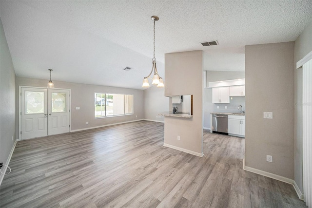 3305 Blythe Ave, Spring Hill, FL 34609 - unfurnished living room with light wood-type flooring, a chandelier, baseboards, a textured ceiling, and vaulted ceiling