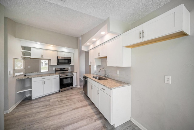 3305 Blythe Ave, Spring Hill, FL 34609 - kitchen featuring stainless steel appliances, a sink, open shelves, light wood finished floors, and baseboards