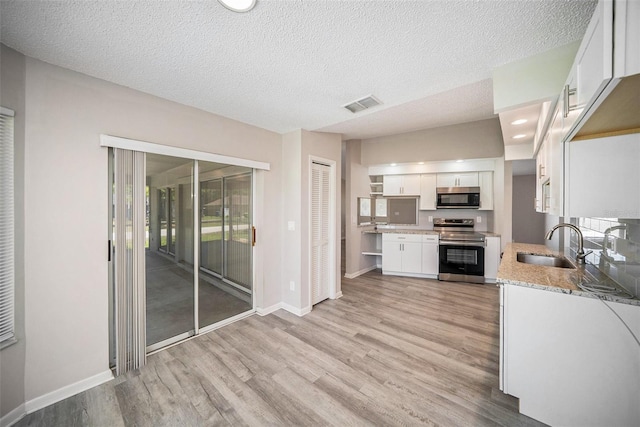 3305 Blythe Ave, Spring Hill, FL 34609 - kitchen with stainless steel appliances, a sink, light wood finished floors, white cabinets, and baseboards