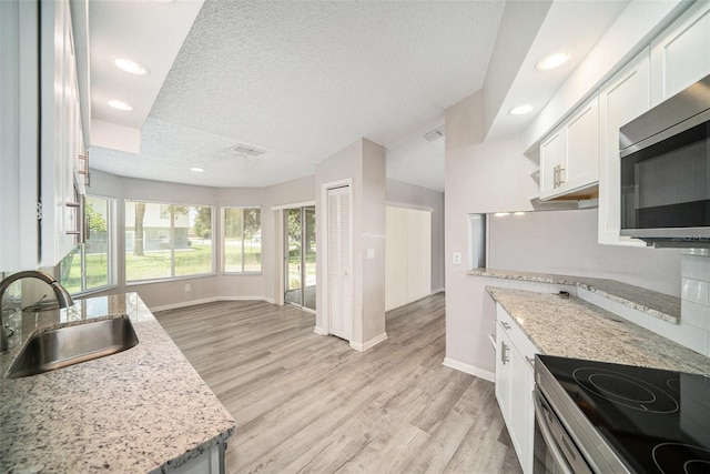 3305 Blythe Ave, Spring Hill, FL 34609 - kitchen featuring stainless steel appliances, a sink, baseboards, white cabinets, and a textured ceiling