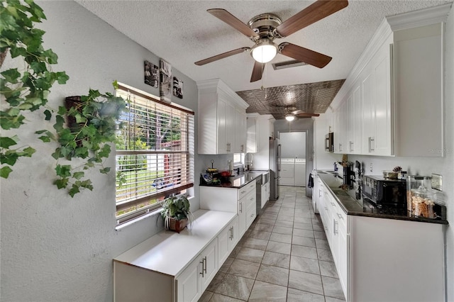 1716 Bayou Cir, Lakeland, FL 33803 - kitchen with a ceiling fan, appliances with stainless steel finishes, white cabinetry, dark countertops, and a textured ceiling