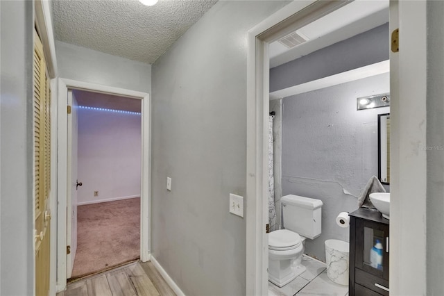 1716 Bayou Cir, Lakeland, FL 33803 - bathroom with toilet, a textured ceiling, vanity, baseboards, and wood finished floors