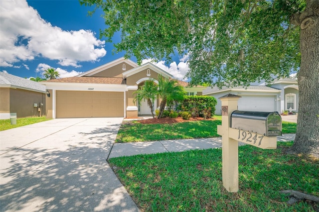 19247 Otters Wick Way, Land O Lakes, FL 34638 - view of front of home featuring stucco siding, a garage, driveway, and a front lawn