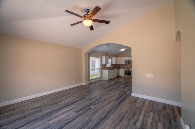 19247 Otters Wick Way, Land O Lakes, FL 34638 - unfurnished living room with lofted ceiling, dark wood finished floors, arched walkways, a ceiling fan, and baseboards