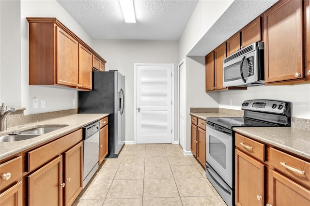 4991 Key Lime Dr Unit 104, Jacksonville, FL 32256 - kitchen with appliances with stainless steel finishes, a sink, a textured ceiling, light tile patterned floors, and brown cabinets
