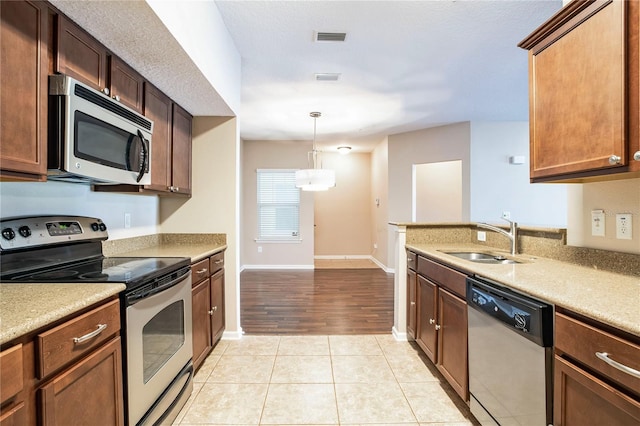 4991 Key Lime Dr Unit 104, Jacksonville, FL 32256 - kitchen featuring appliances with stainless steel finishes, a sink, decorative light fixtures, baseboards, and light tile patterned floors