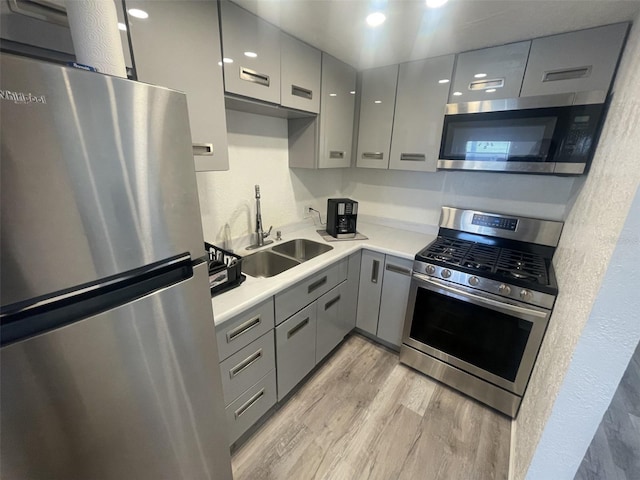 2011 58th Ave N Unit 20, Saint Petersburg, FL 33714 - kitchen featuring stainless steel appliances, gray cabinets, a sink, light wood finished floors, and light countertops