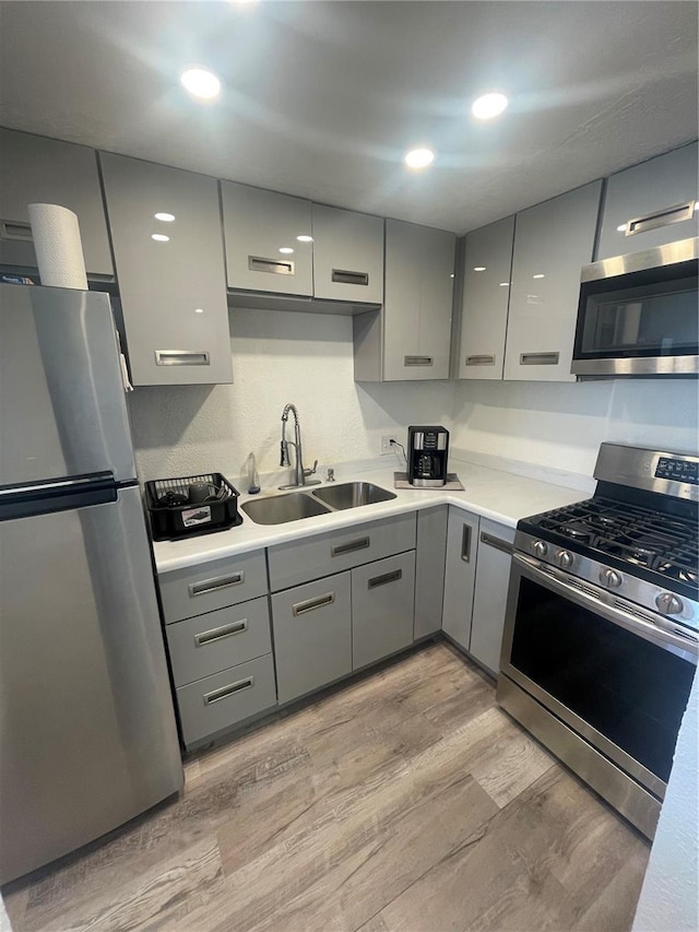 2011 58th Ave N Unit 20, Saint Petersburg, FL 33714 - kitchen with stainless steel appliances, a sink, gray cabinetry, light wood-style flooring, and light countertops