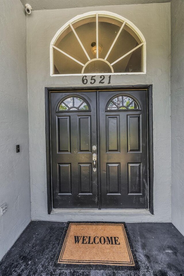 6521 Oelsner St, New Port Richey, FL 34652 - view of exterior entry featuring stucco siding and a surveillance system