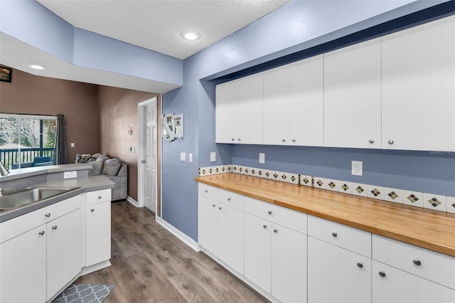 6521 Oelsner St, New Port Richey, FL 34652 - kitchen featuring a sink, a textured ceiling, wood finished floors, wood counters, and white cabinets