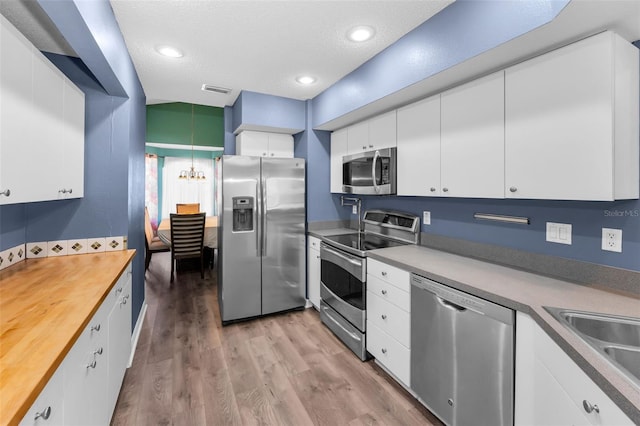 6521 Oelsner St, New Port Richey, FL 34652 - kitchen with appliances with stainless steel finishes, a sink, white cabinets, light wood-style flooring, and wooden counters
