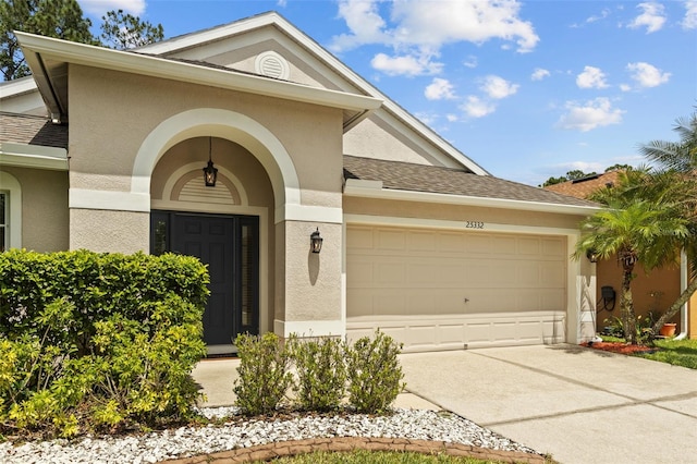 25332 Lexington Oaks Blvd, Wesley Chapel, FL 33544 - view of front of home featuring an attached garage, stucco siding, driveway, and roof with shingles
