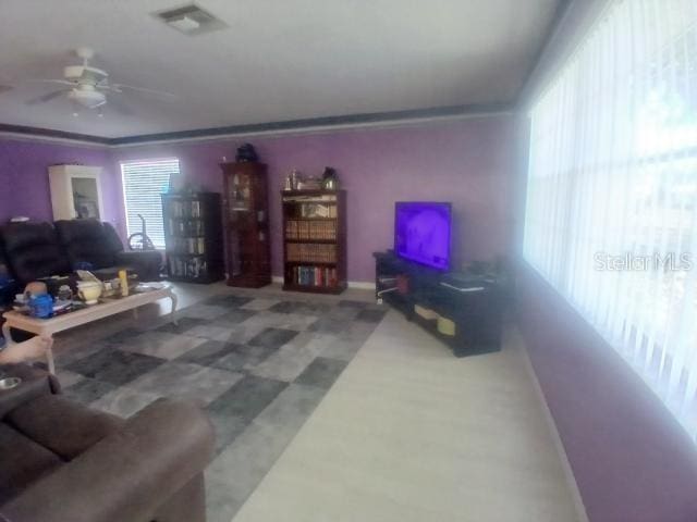 living area with ceiling fan, tile patterned floors, crown molding, and baseboards