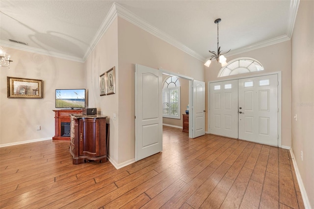 25942 Risen Star Dr, Wesley Chapel, FL 33544 - entrance foyer with a chandelier, ornamental molding, light wood-style flooring, and a fireplace with raised hearth