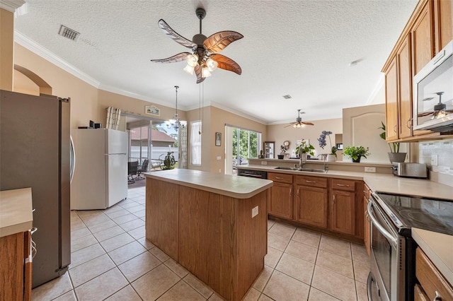 25942 Risen Star Dr, Wesley Chapel, FL 33544 - kitchen with stainless steel appliances, a ceiling fan, brown cabinetry, light countertops, and light tile patterned floors