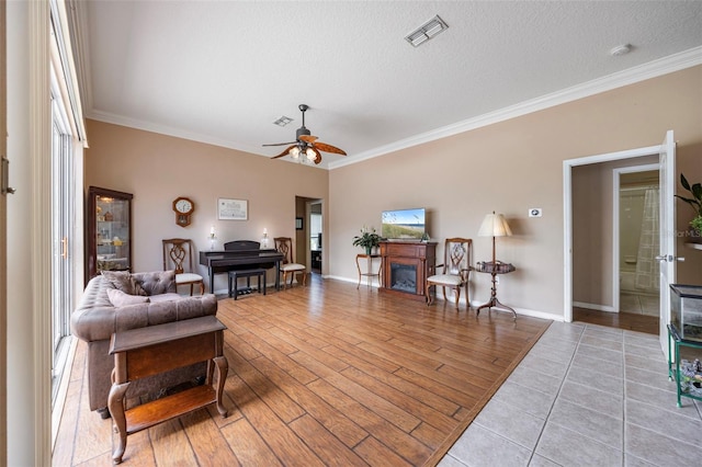 25942 Risen Star Dr, Wesley Chapel, FL 33544 - living area with ornamental molding, a fireplace, ceiling fan, a textured ceiling, and wood finished floors